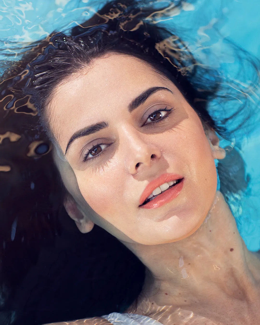 Kvinde med perfekte bryn og strålende hud ligger i vand